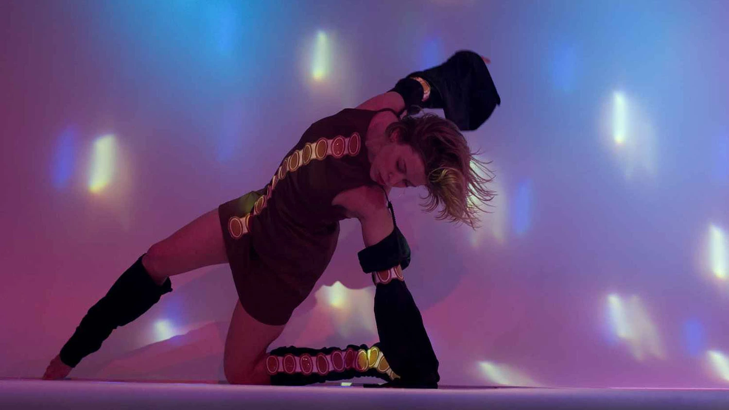 Gabrielle Eychenne danse sur scène dans une création chorégraphique disco aux lumières rouges et bleues