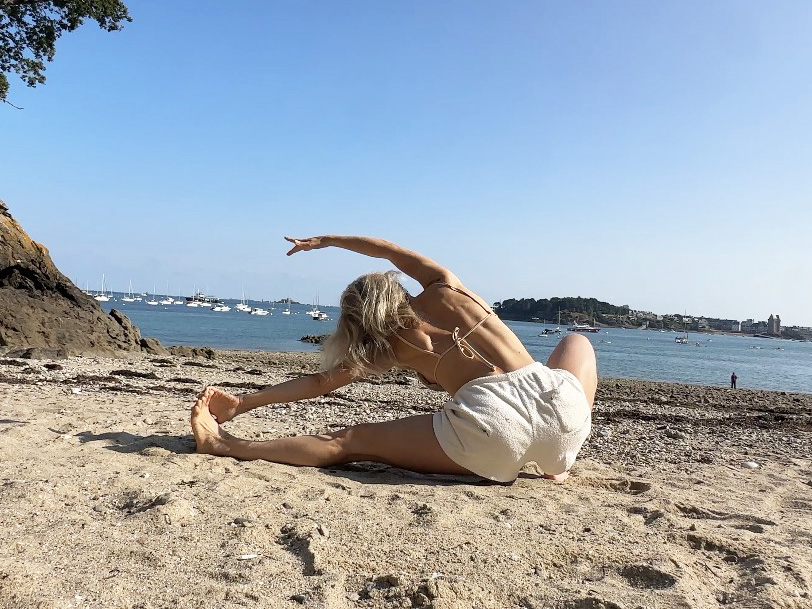 Gabrielle Eychenne pratiquant un exercice de Pilates en extérieur au bord de la mer